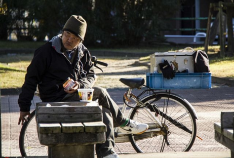 在公園的一角,一個乞丐正在享用剛剛買回來的方便麵.